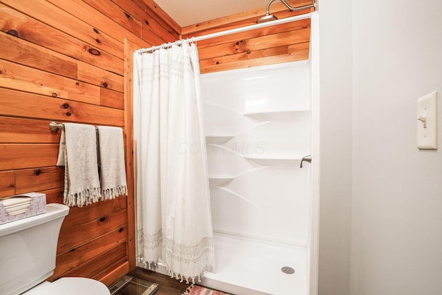 bathroom with wooden walls, toilet, and walk in shower