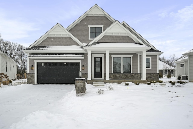 view of front of home with central air condition unit, stone siding, and a garage