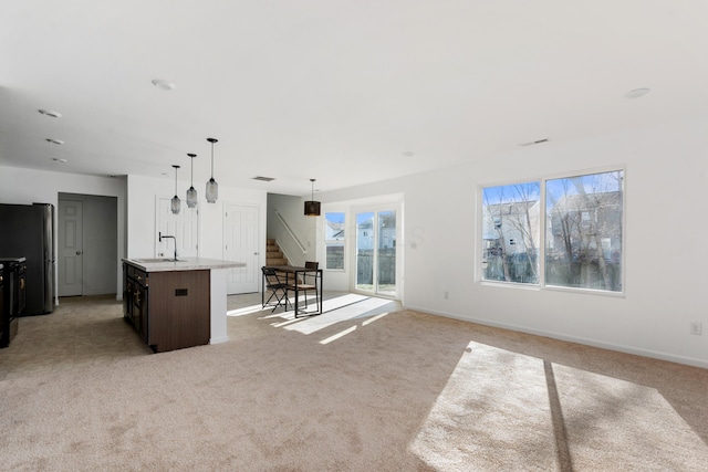 unfurnished living room with sink and light carpet