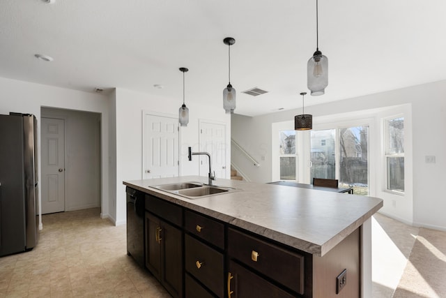 kitchen featuring sink, a center island with sink, stainless steel refrigerator, and decorative light fixtures