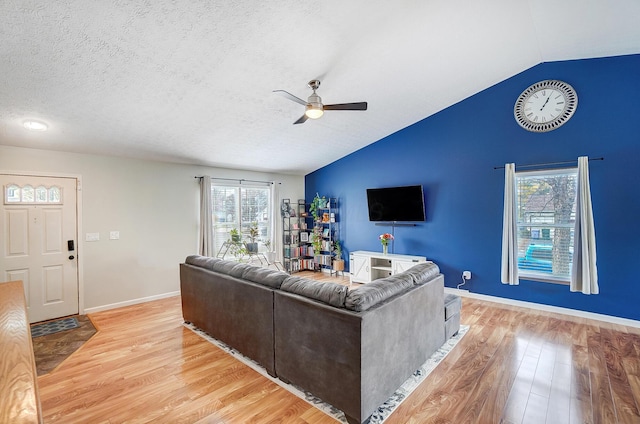 living room with lofted ceiling, a textured ceiling, ceiling fan, and light hardwood / wood-style flooring