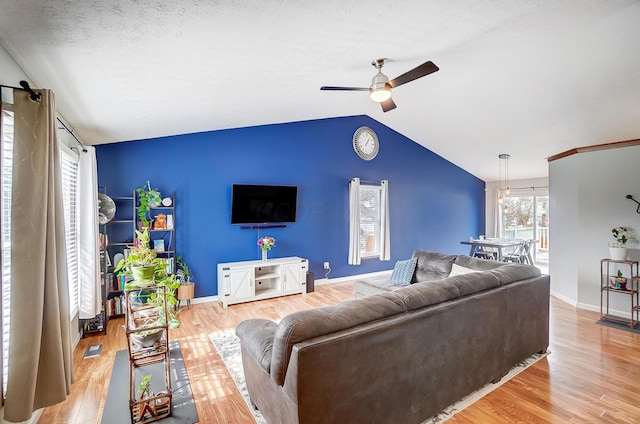 living room with lofted ceiling, a textured ceiling, light hardwood / wood-style floors, and ceiling fan