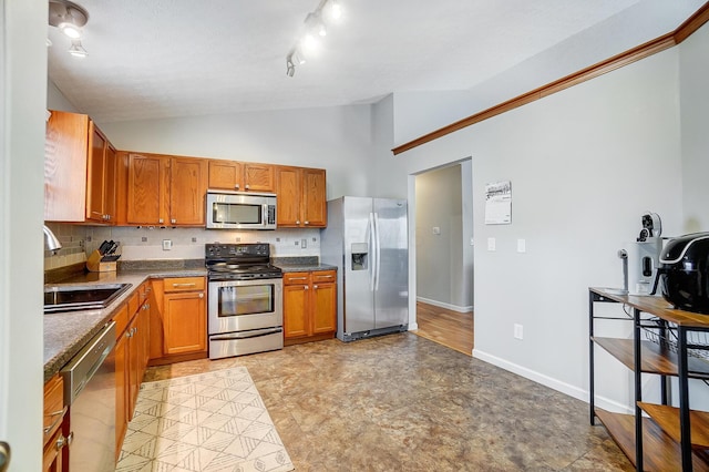 kitchen featuring stainless steel appliances, vaulted ceiling, sink, and tasteful backsplash