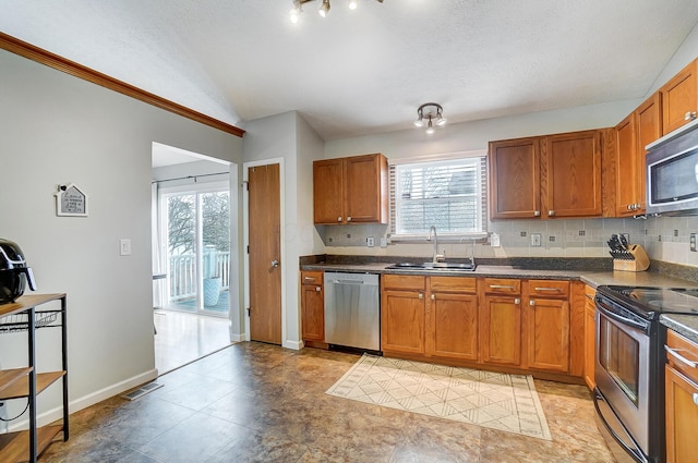 kitchen with lofted ceiling, sink, stainless steel appliances, tasteful backsplash, and a textured ceiling