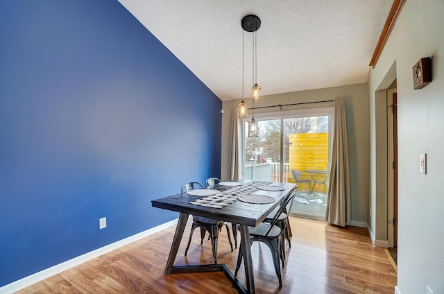 dining room featuring hardwood / wood-style flooring, lofted ceiling, and a textured ceiling