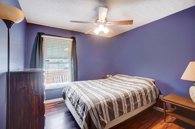 bedroom with ceiling fan, a textured ceiling, and dark hardwood / wood-style flooring