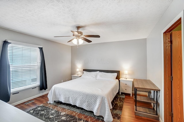 bedroom featuring ceiling fan, wood-type flooring, and a textured ceiling