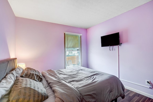 bedroom featuring dark hardwood / wood-style flooring and a textured ceiling