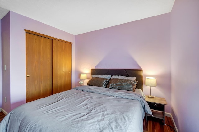 bedroom with dark hardwood / wood-style flooring and a closet