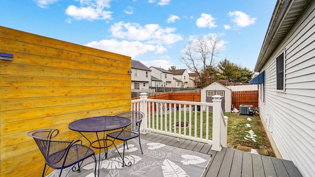 wooden terrace featuring a shed, a yard, and central AC