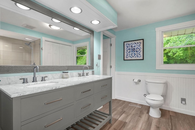 bathroom with vanity, toilet, hardwood / wood-style floors, and a tile shower