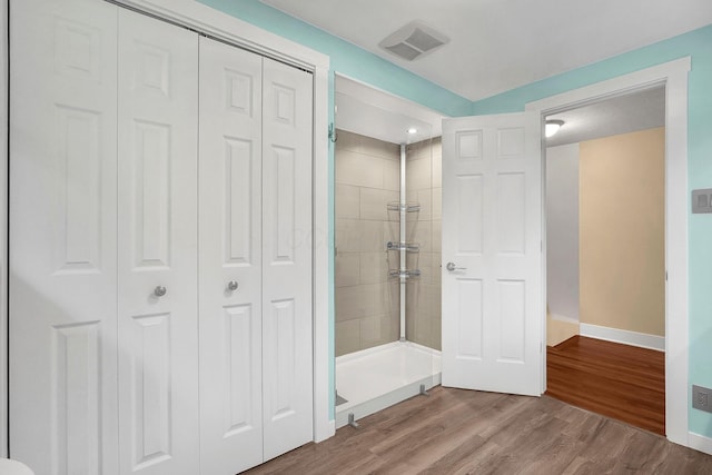 bathroom with a tile shower and hardwood / wood-style floors