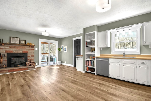 kitchen with sink, white cabinetry, a textured ceiling, appliances with stainless steel finishes, and light hardwood / wood-style floors