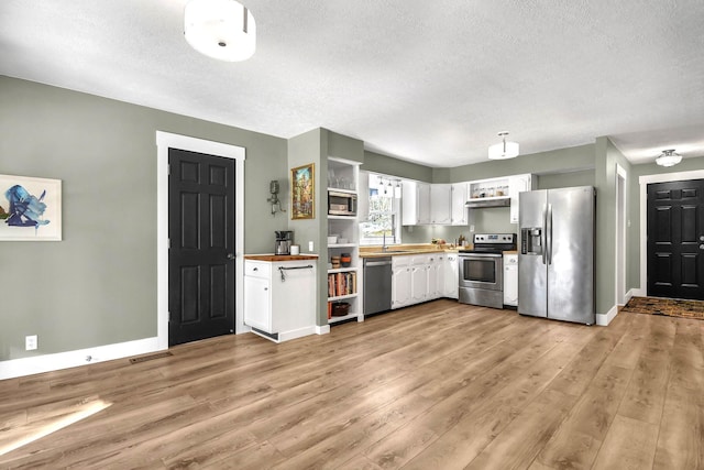 kitchen with stainless steel appliances, wooden counters, white cabinets, and light hardwood / wood-style flooring