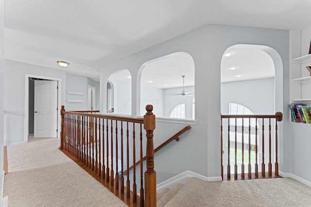 corridor featuring baseboards, an upstairs landing, and carpet