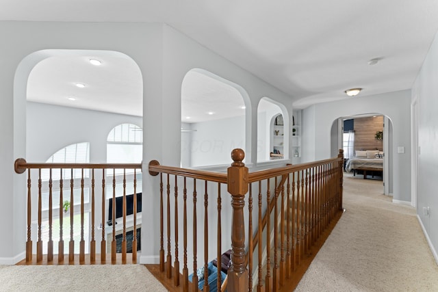 corridor featuring carpet flooring, baseboards, and an upstairs landing