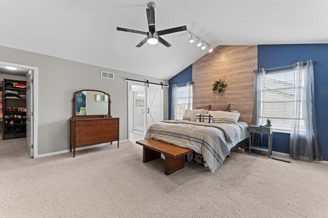 carpeted bedroom featuring wood walls, vaulted ceiling, visible vents, a walk in closet, and baseboards