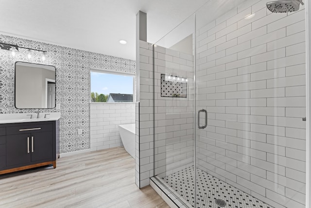 bathroom with a soaking tub, a stall shower, recessed lighting, wood finished floors, and vanity