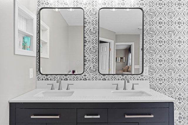 full bath with a sink, wallpapered walls, and double vanity
