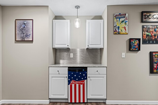 kitchen featuring tasteful backsplash, pendant lighting, baseboards, and white cabinetry