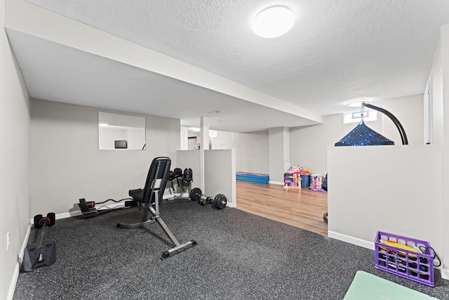 exercise area with baseboards and a textured ceiling