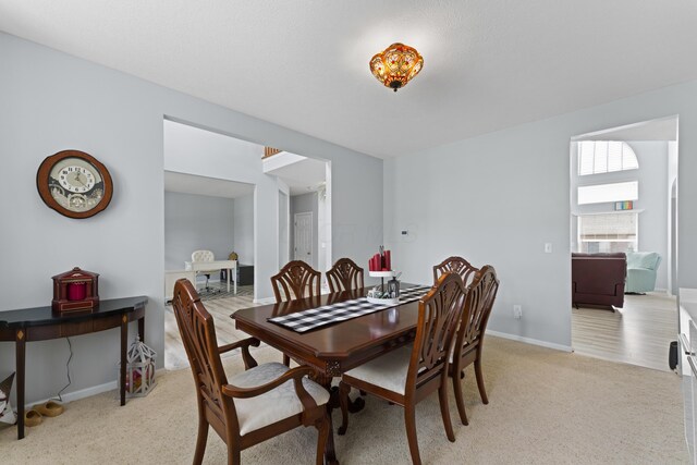 dining space with baseboards and light colored carpet