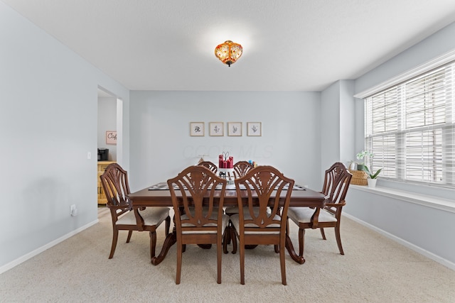 dining area featuring baseboards and light colored carpet
