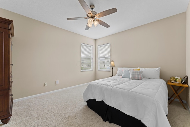 bedroom featuring light carpet, a ceiling fan, and baseboards