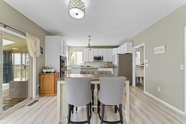 dining room with light wood-style flooring, visible vents, and baseboards