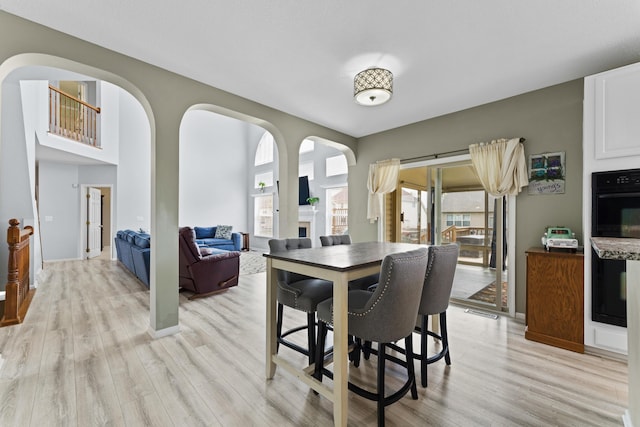 dining area featuring arched walkways, light wood-style flooring, visible vents, and baseboards