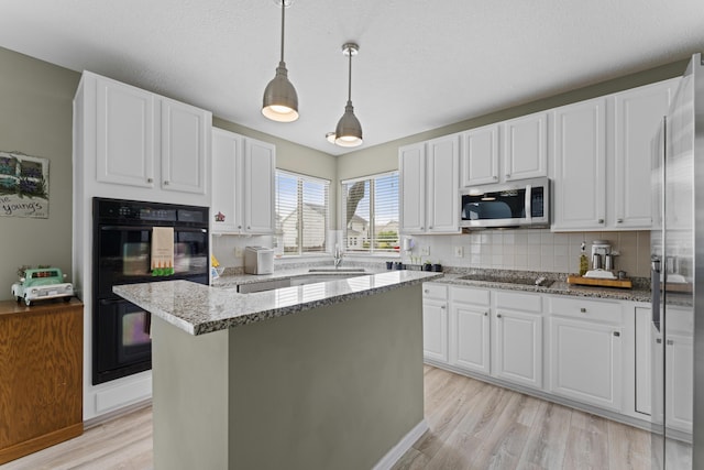 kitchen with black appliances, backsplash, white cabinetry, and light wood-style flooring