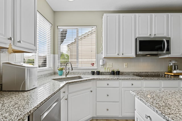 kitchen with white cabinets, a wealth of natural light, appliances with stainless steel finishes, and a sink