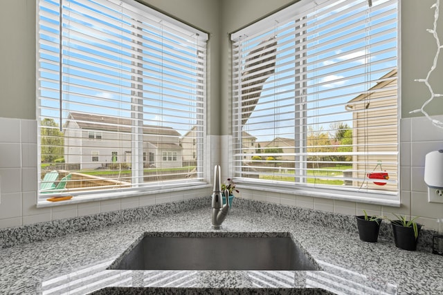interior details featuring backsplash, light stone countertops, and a sink