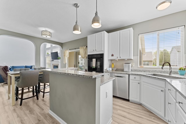 kitchen featuring light wood-style floors, dishwasher, oven, and a sink