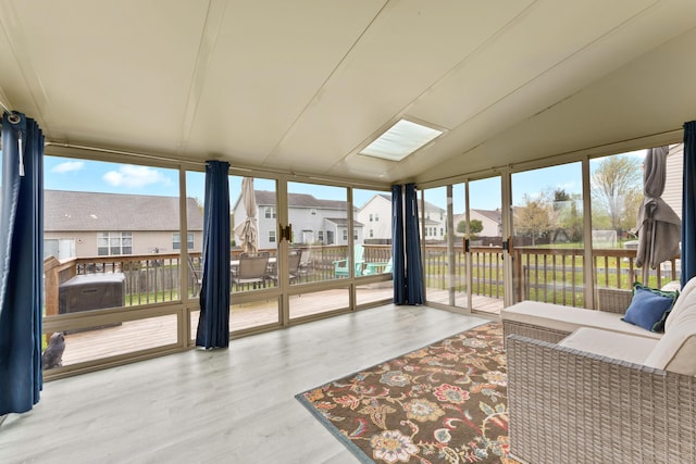 sunroom featuring lofted ceiling, a residential view, a wall of windows, and wood finished floors