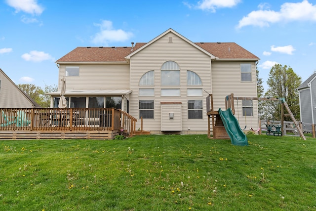back of house featuring a wooden deck, a sunroom, a yard, and a playground