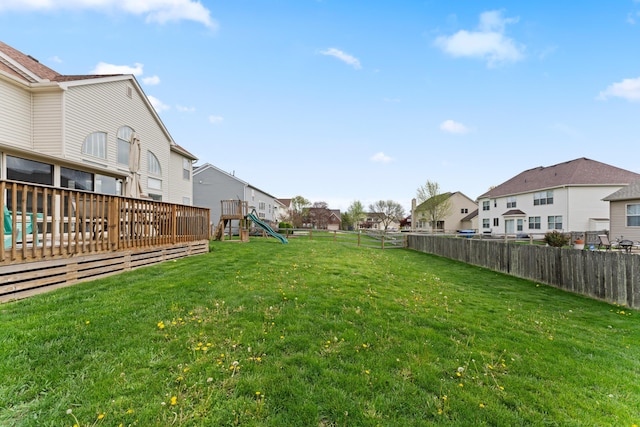 view of yard featuring a fenced backyard, a deck, a residential view, and a playground