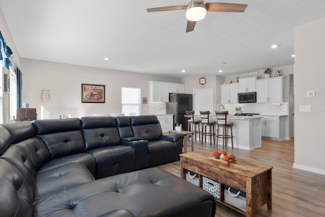 living room featuring a textured ceiling, ceiling fan, and light wood-type flooring