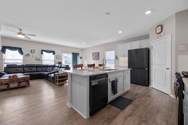 kitchen with an island with sink, sink, white cabinets, and black appliances