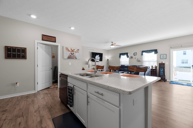 kitchen featuring sink, black dishwasher, an island with sink, white cabinets, and dark hardwood / wood-style flooring