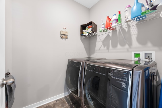 clothes washing area featuring dark tile patterned floors and washing machine and clothes dryer