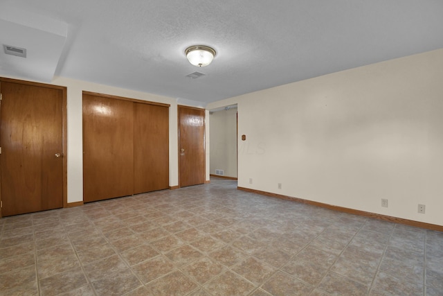 unfurnished bedroom with a textured ceiling and two closets