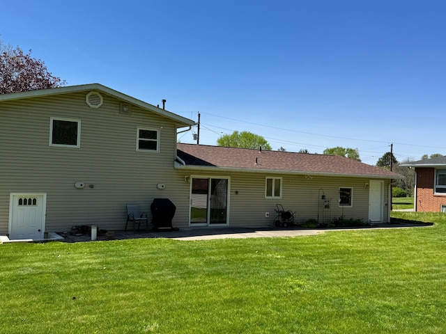 back of property with a yard, a patio, and a shingled roof