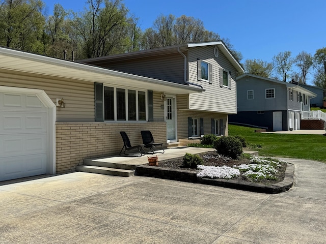 back of house with driveway, a yard, and brick siding