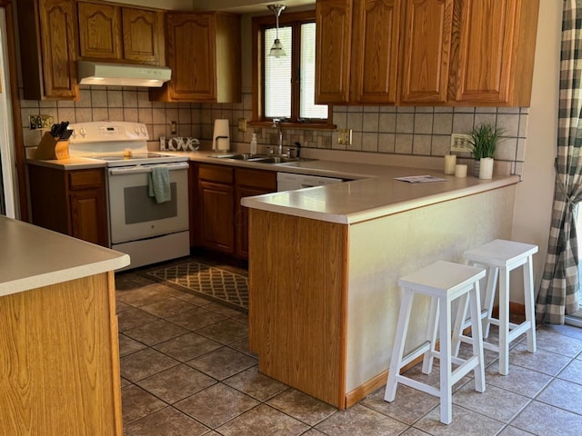 kitchen featuring decorative backsplash, white range with electric cooktop, under cabinet range hood, a sink, and a peninsula