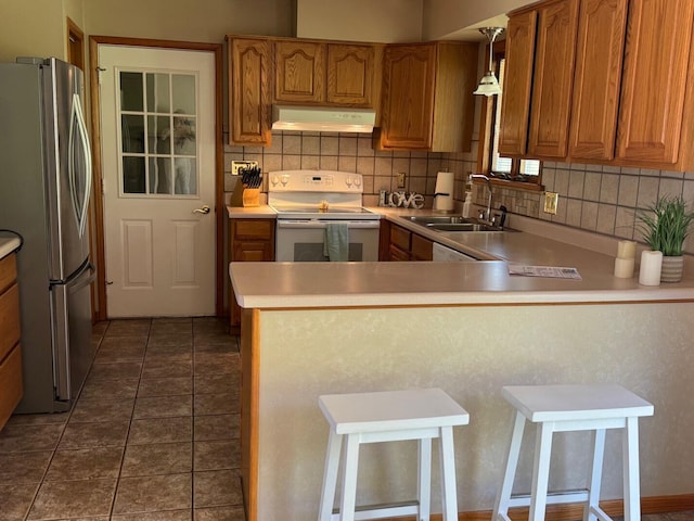 kitchen featuring tasteful backsplash, a sink, extractor fan, freestanding refrigerator, and white range with electric cooktop