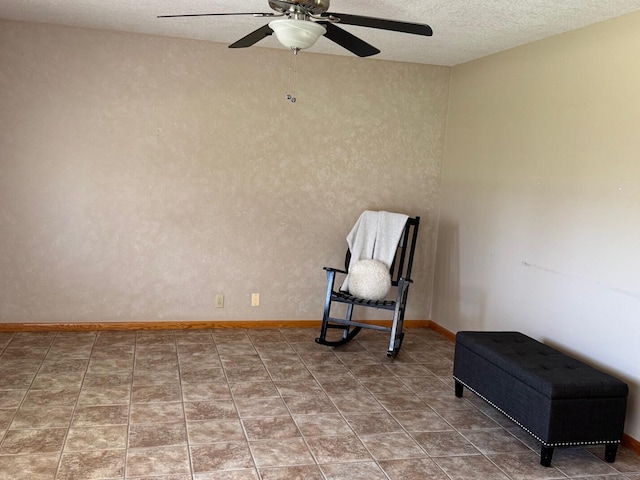 living area with baseboards, ceiling fan, and a textured ceiling