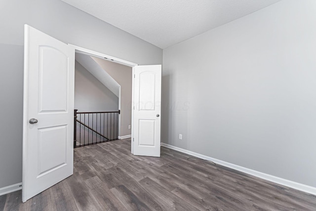 additional living space with dark wood-type flooring and a textured ceiling