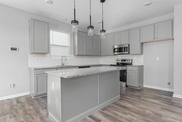 kitchen with sink, stainless steel appliances, light stone countertops, and a kitchen island