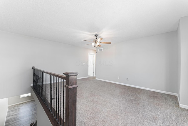 spare room with a textured ceiling, ceiling fan, and carpet flooring